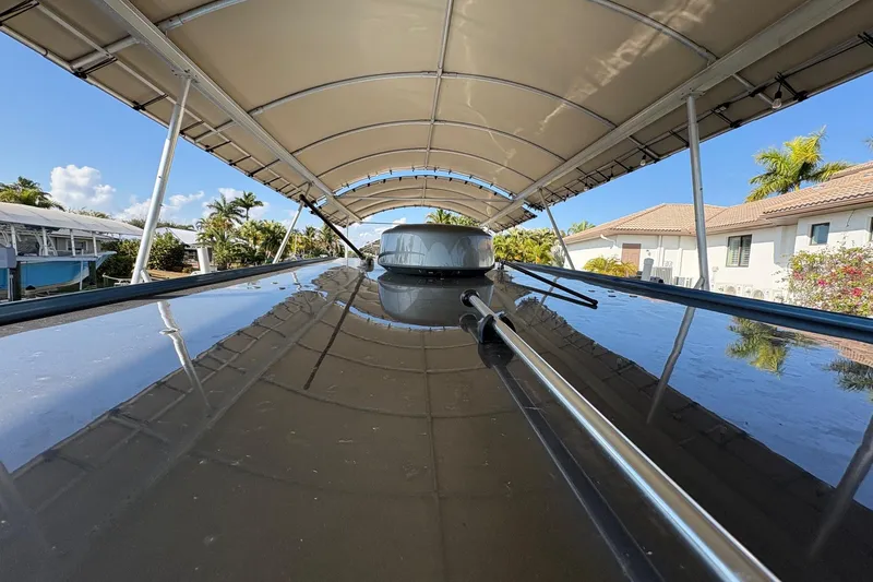 Slide: The Image of 2023 Nor-Tech 390 Sport Center Console under canopy, reflecting clear blue sky and tropical surroundings. - 16