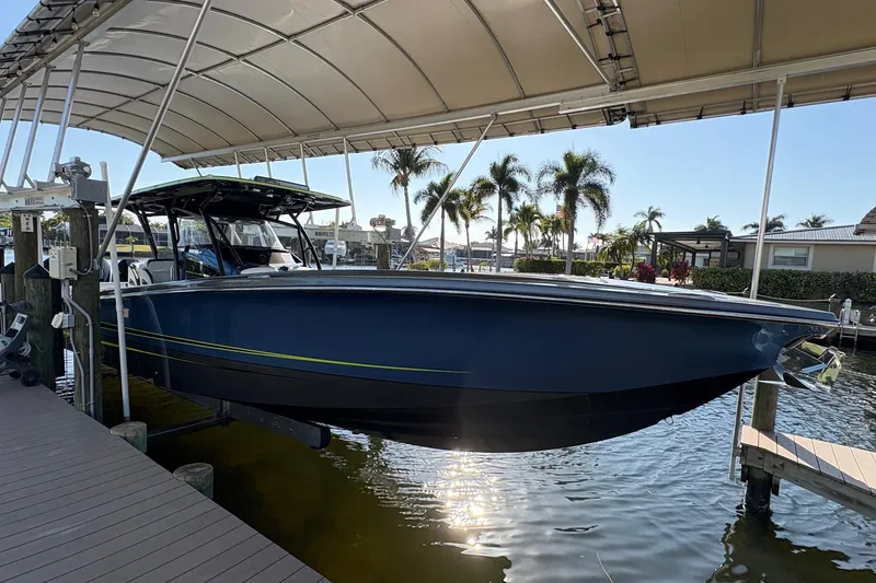 Slide: The Image of 2023 Nor-Tech 390 Sport Center Console boat docked under canopy with palm trees in background. - 3