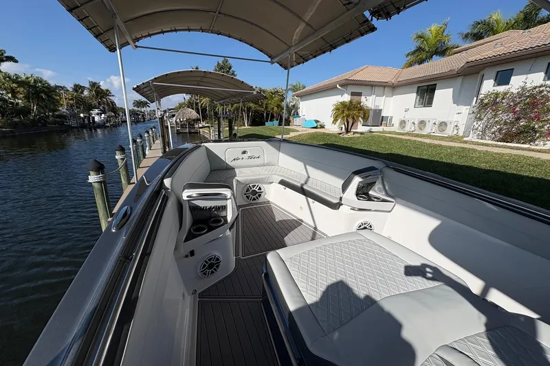 Slide: The Image of 2023 Nor-Tech 390 Sport Center Console boat docked by a canal, featuring luxurious seating. - 7