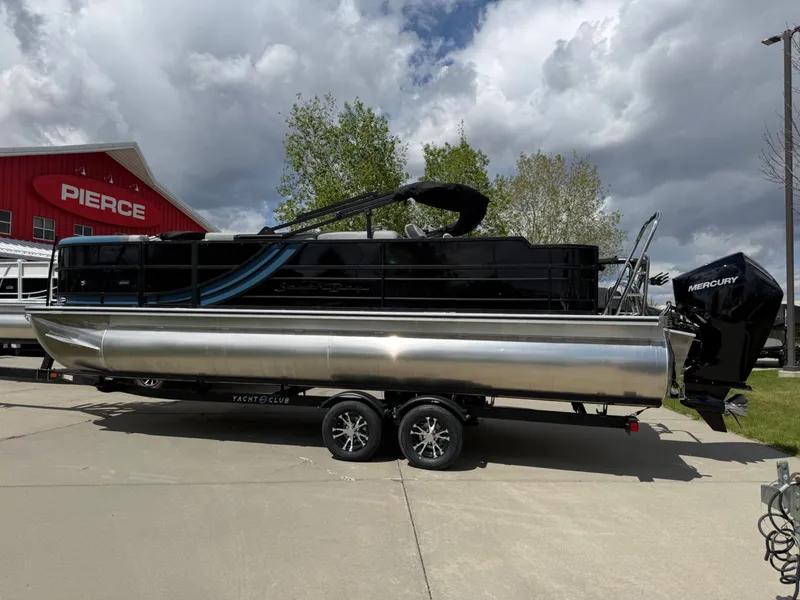 Slide: The Image of 2026 South Bay S224FCR pontoon boat on trailer in front of building. - 3