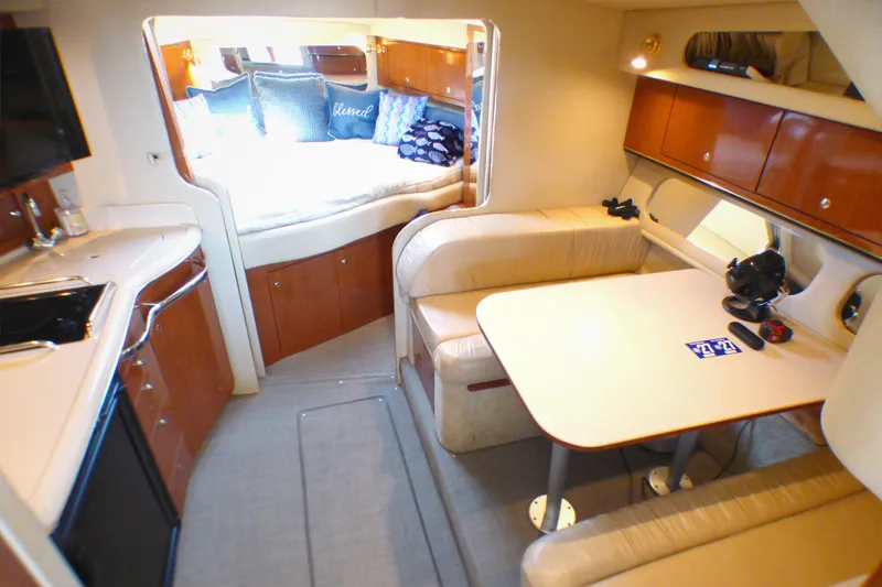 Slide: The Image of Interior of 2002 Sea Ray 340 Amberjack, featuring cozy seating and a compact kitchen area. - 8