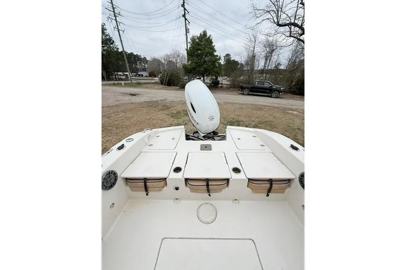 Slide: The Image of 2024 Carolina Skiff 24 Ultra Elite boat with storage compartments and outboard motor. - 14