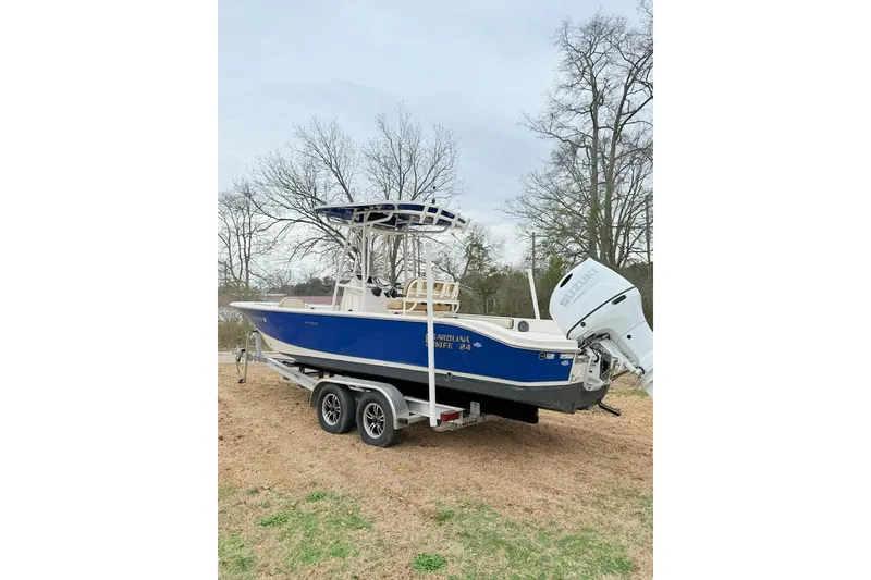 Slide: The Image of 2024 Carolina Skiff 24 Ultra Elite boat on trailer, blue hull, parked outdoors. - 2
