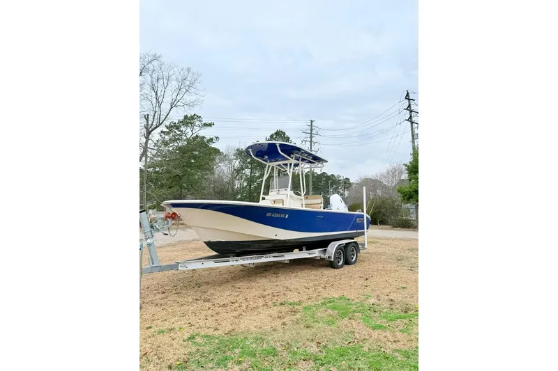 Slide: The Image of 2024 Carolina Skiff 24 Ultra Elite boat on trailer, blue and white design. - 4