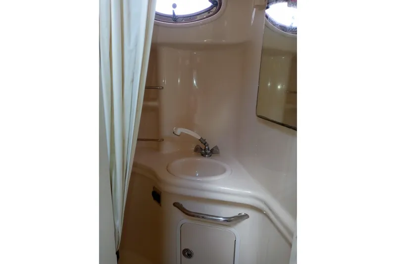 Slide: The Image of 2005 Sea Ray 300 Sundancer bathroom with sink, mirror, and porthole window. - 11