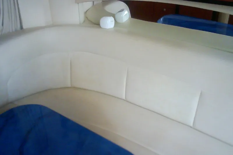 Slide: The Image of Interior seating of 2005 Sea Ray 300 Sundancer with beige upholstery and blue accents. - 26
