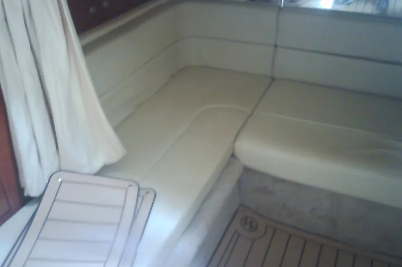 Slide: The Image of Interior seating of 2005 Sea Ray 300 Sundancer with beige upholstery and wooden accents. - 27