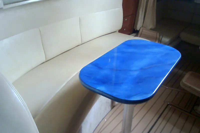 Slide: The Image of Interior of 2005 Sea Ray 300 Sundancer with blue table and beige seating. - 32