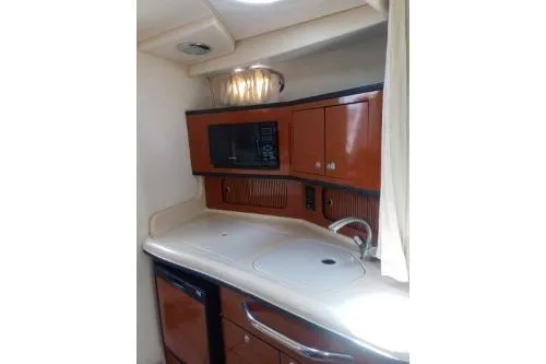 Slide: The Image of 2005 Sea Ray 300 Sundancer galley with microwave, sink, and storage cabinets. - 9