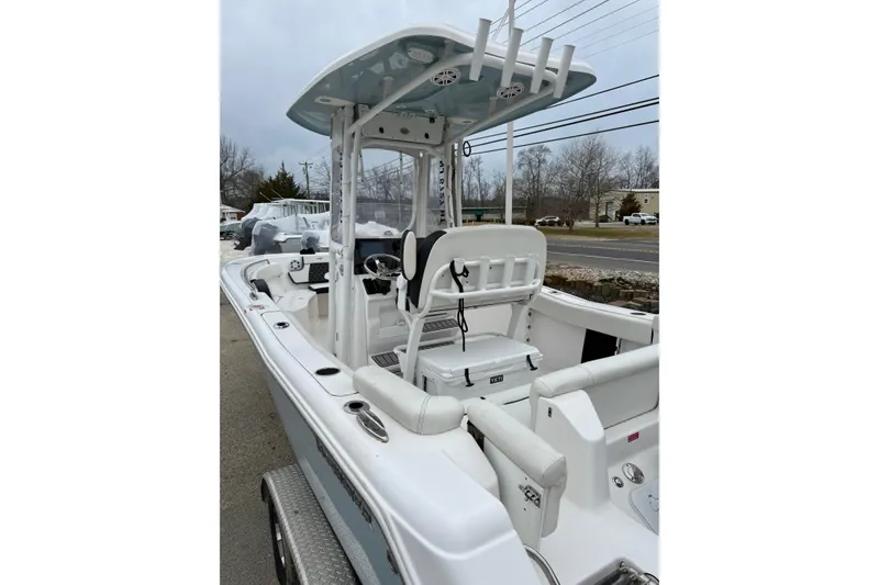 Slide: The Image of 2023 Tidewater 220 LXF boat with T-top and seating, parked on a trailer. - 13