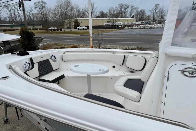 Slide: The Image of 2023 Tidewater 220 LXF boat interior with seating and table, parked outdoors. - 17