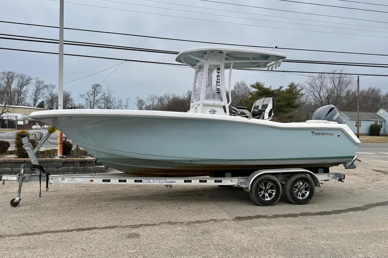 Slide: The Image of 2023 Tidewater 220 LXF boat on trailer, light blue hull, parked outdoors. - 8