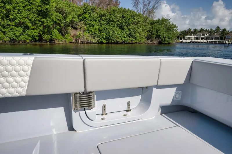 Slide: The Image of 2025 Contender 44 ST boat interior with sleek seating, near lush greenery and waterfront homes. - 36