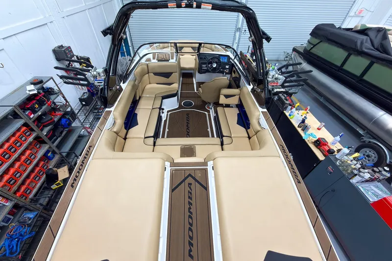 Slide: The Image of 2020 Moomba Kaiyen boat interior with beige seating and modern dashboard in a garage setting. - 13