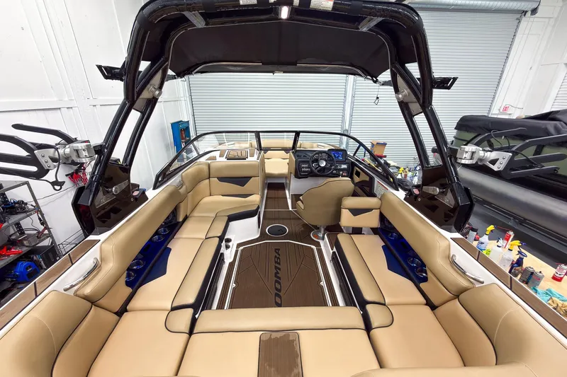 Slide: The Image of 2020 Moomba Kaiyen boat interior with tan seating and modern dashboard in a garage setting. - 14