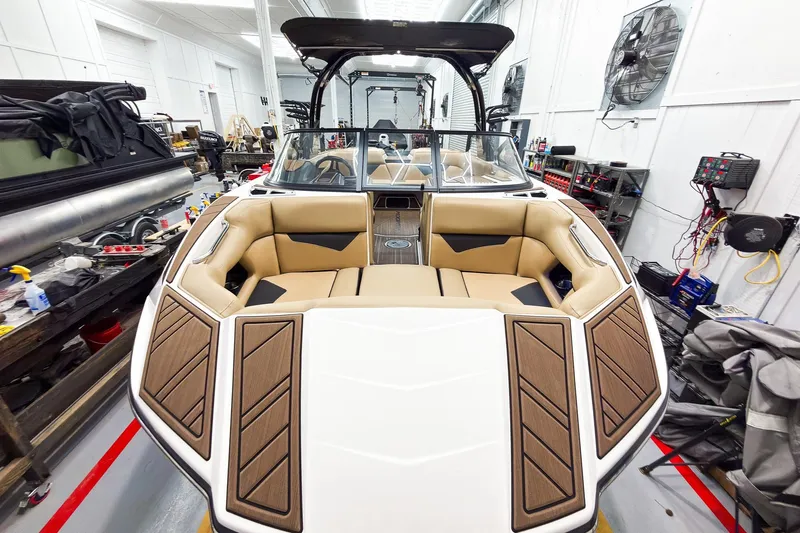 Slide: The Image of 2020 Moomba Kaiyen boat interior in a workshop, featuring tan seating and wood accents. - 9