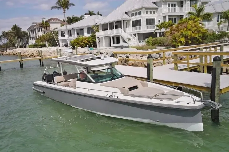 The Image of 2024 Axopar 37 Sun-Top boat docked near luxury waterfront homes. - 1