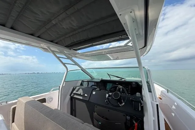 Slide: The Image of 2024 Axopar 37 Sun-Top boat interior with ocean view, featuring modern helm and seating. - 10