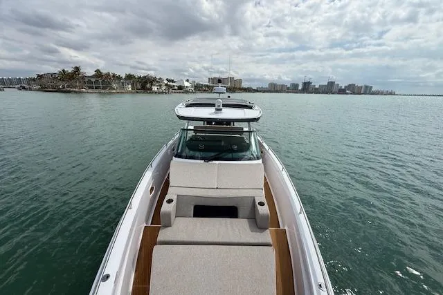 Slide: The Image of 2024 Axopar 37 Sun-Top boat cruising on calm waters under a cloudy sky. - 13