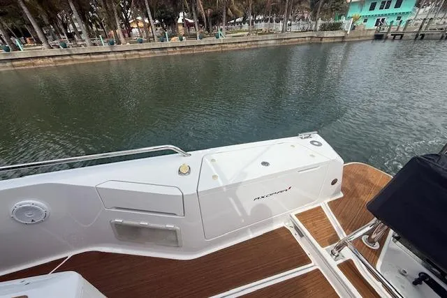 Slide: The Image of 2024 Axopar 37 Sun-Top boat deck with wood finish, docked by calm waters. - 14
