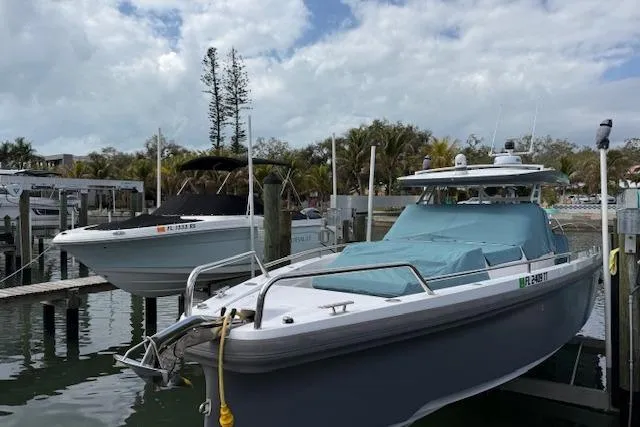 Slide: The Image of 2024 Axopar 37 Sun-Top boat docked in a marina under cloudy skies. - 21