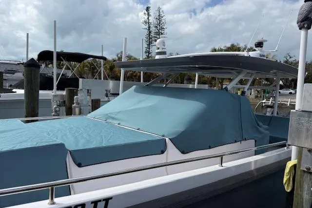 Slide: The Image of 2024 Axopar 37 Sun-Top boat docked, covered with blue tarpaulin. - 22