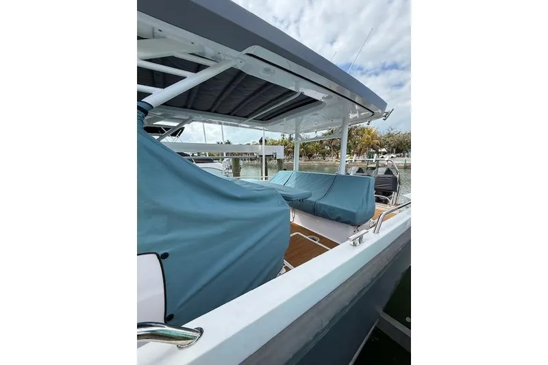 Slide: The Image of 2024 Axopar 37 Sun-Top boat with covered seating, docked by the water. - 23