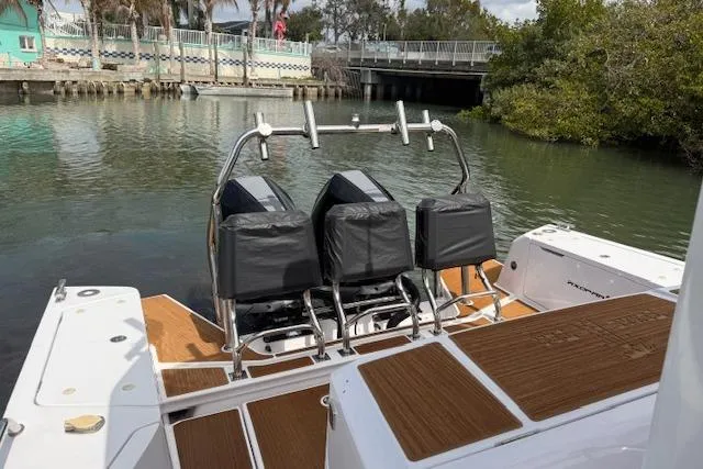 Slide: The Image of 2024 Axopar 37 Sun-Top boat with dual seats, docked near a bridge. - 5