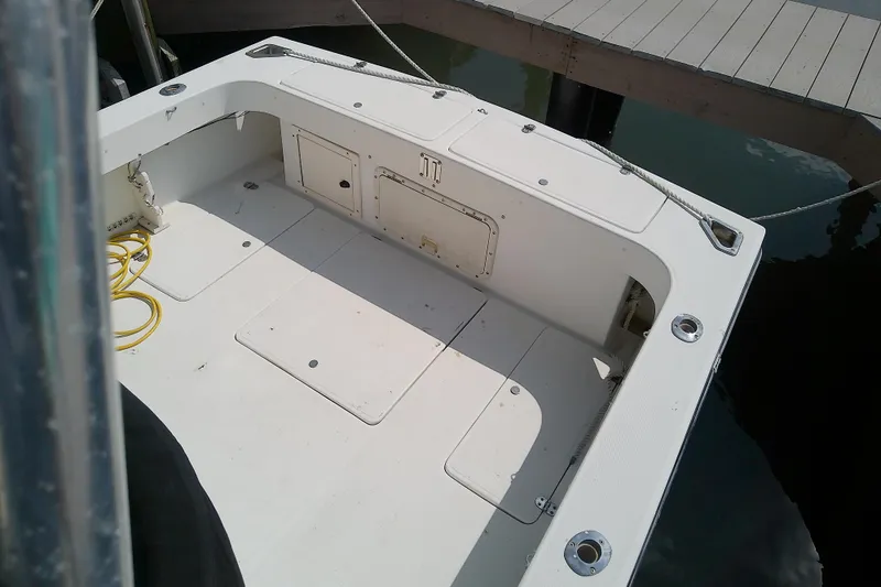 Slide: The Image of 1996 Shamrock 260 Express boat deck with storage compartments and docked at marina. - 12
