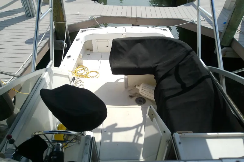 Slide: The Image of 1996 Shamrock 260 Express boat interior at dock, featuring covered seating and steering wheel. - 11