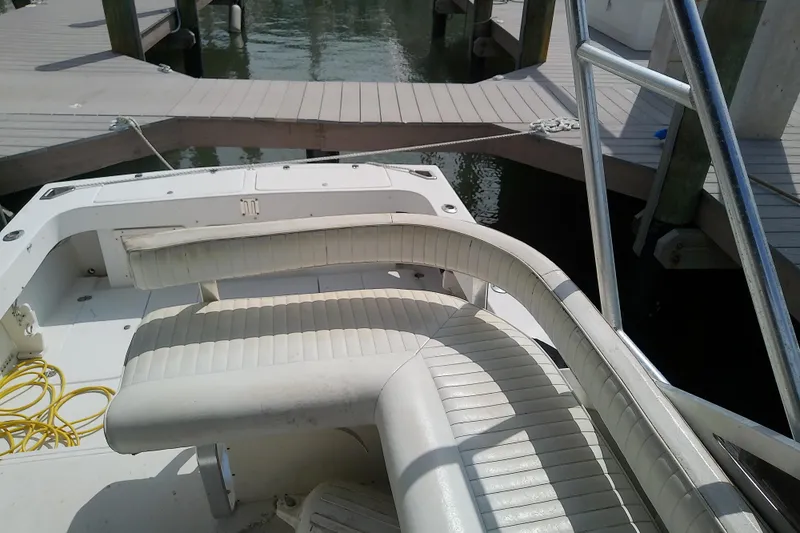Slide: The Image of 1996 Shamrock 260 Express boat interior with white seating and dock view. - 14