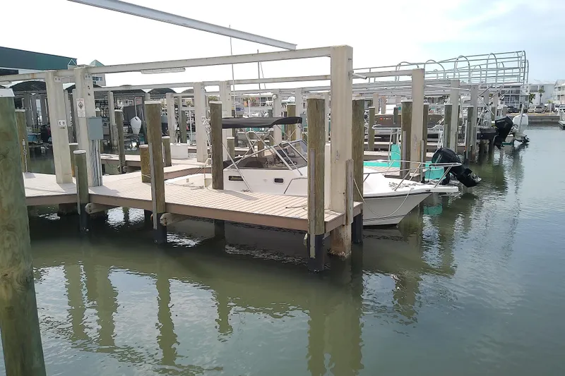 Slide: The Image of 1996 Shamrock 260 Express boat docked at a marina with wooden piers. - 3