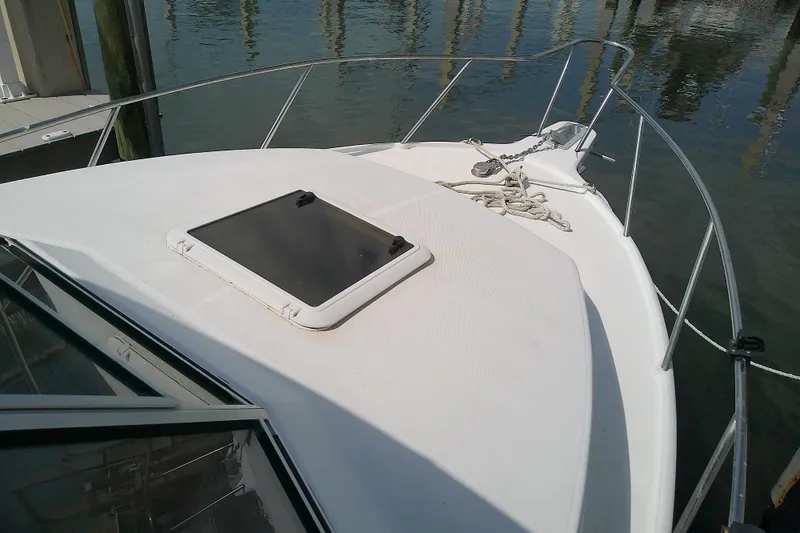 Slide: The Image of 1996 Shamrock 260 Express boat deck with hatch and railing, docked by calm water. - 9