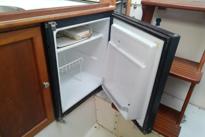 Slide: The Image of Open mini fridge on 1996 Shamrock 260 Express boat, showing interior shelves and wooden cabinetry. - 29