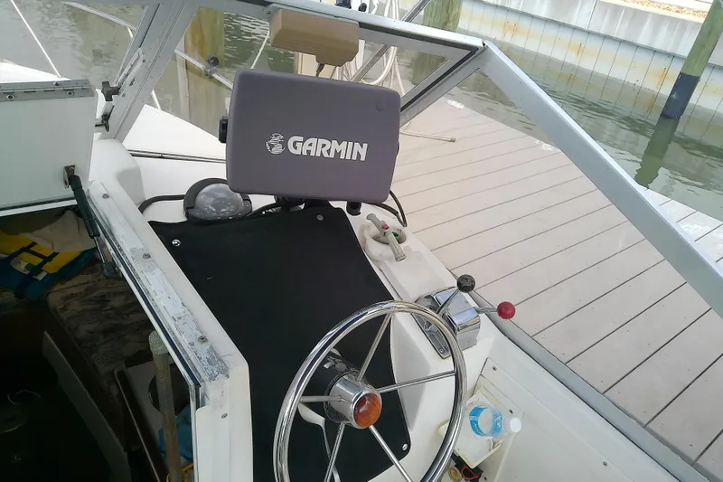 Slide: The Image of 1996 Shamrock 260 Express boat helm with Garmin GPS, docked by wooden pier. - 17