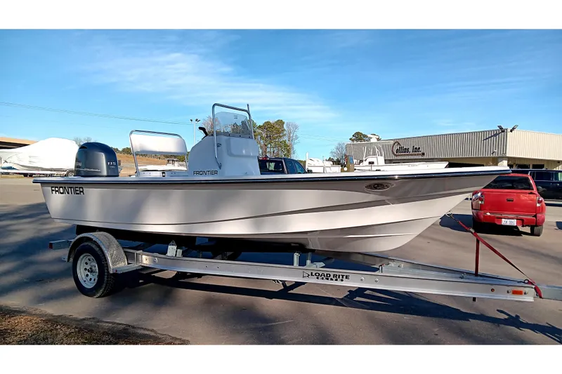 Slide: The Image of 2026 Frontier 180 boat on trailer under cloudy sky at dealership. - 5