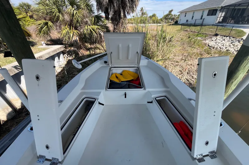 Slide: The Image of 2022 KenCraft 239 Bay Rider boat with open storage compartments, docked near lush greenery. - 15