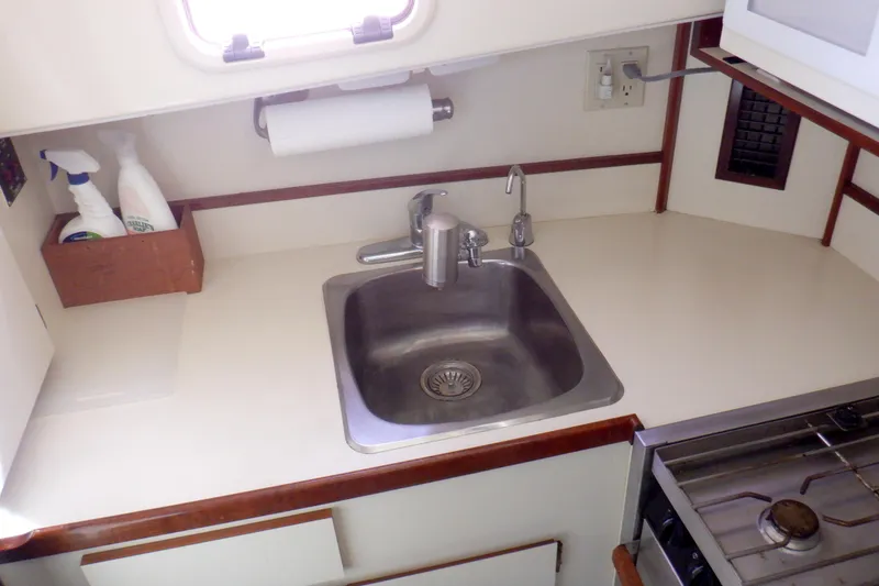 Slide: The Image of 2004 Camano 31 Troll boat kitchen with sink, stove, and cleaning supplies. - 29