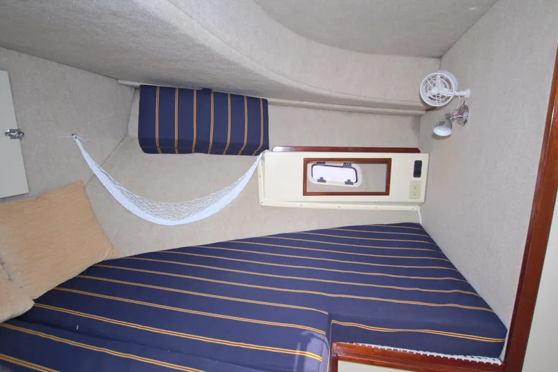 Slide: The Image of 2004 Camano 31 Troll cabin interior with striped bedding and small fan. - 36