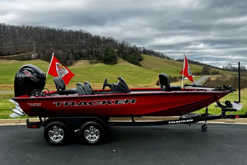 The Image of 2026 Tracker Pro Team 195 boat with flags, parked on a scenic road. - 0