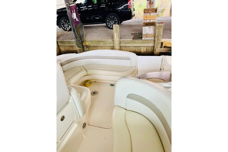 Slide: The Image of 2002 Sea Ray Sundancer 320 interior with cream seating, docked near a black vehicle. - 13