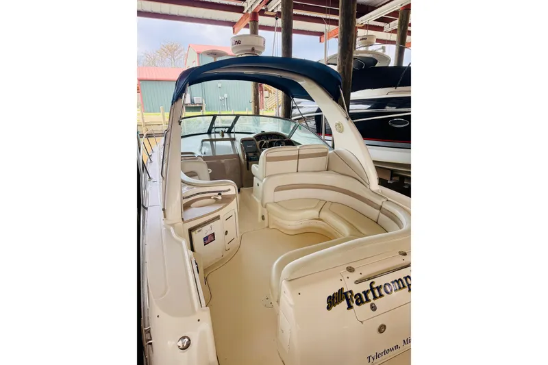 Slide: The Image of 2002 Sea Ray Sundancer 320 with spacious seating and helm, docked under a covered marina. - 2