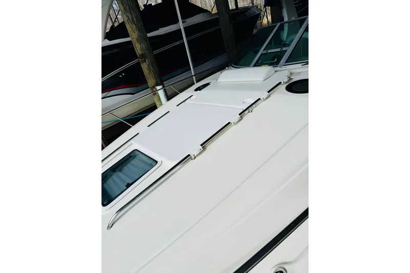 Slide: The Image of 2002 Sea Ray Sundancer 320 boat deck with sleek design and windows. - 8