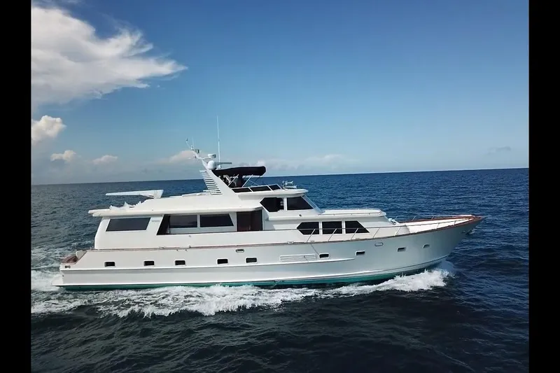 Slide: The Image of 1984 Broward CPMY Raised Pilothouse yacht cruising on open sea under clear blue sky. - 142