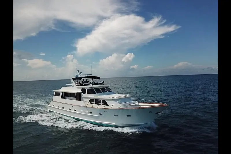 Slide: The Image of 1984 Broward CPMY Raised Pilothouse yacht cruising on open sea under blue sky. - 144