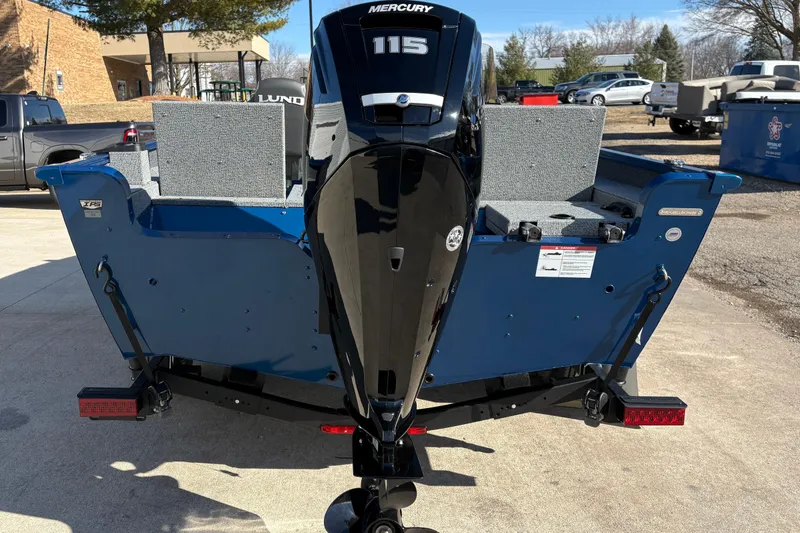 Slide: The Image of 2026 Lund 1775 Adventure SS boat with Mercury 115 engine, parked outdoors. - 2