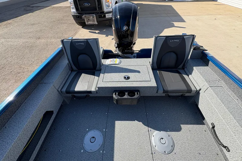 Slide: The Image of 2026 Lund 1775 Adventure SS boat interior with seating and motor, parked on pavement. - 22