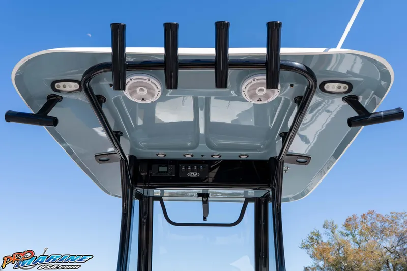 Slide: The Image of 2023 Sea Hunt Ultra 255 SE boat T-top with rod holders and speakers against blue sky. - 21