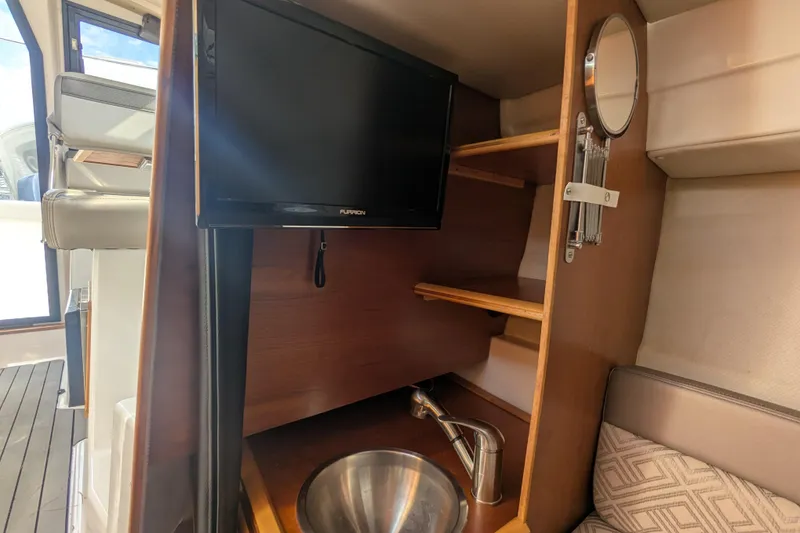Slide: The Image of 2020 Cutwater C-24 Coupe interior with TV, sink, and wooden shelves. - 12
