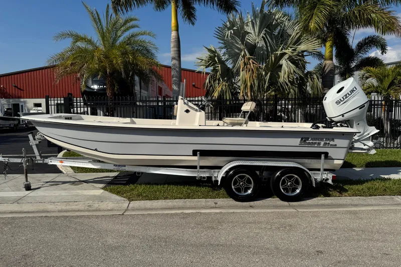 The Image of 2023 Carolina Skiff 21 SWS boat on trailer, parked near palm trees. - 0